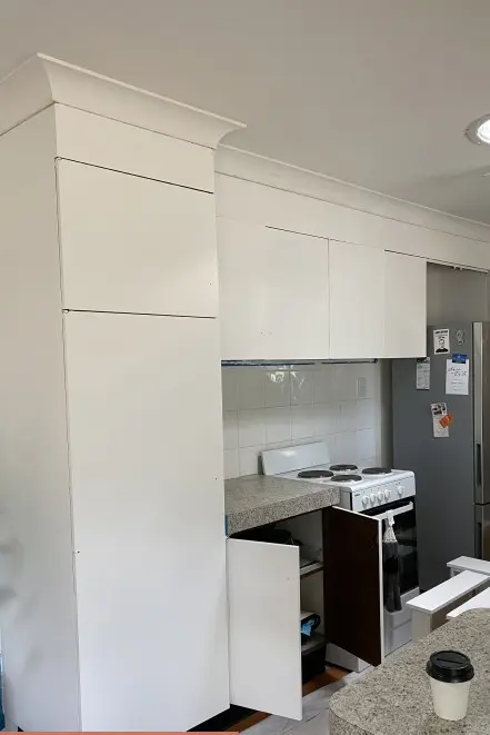 White kitchen with stove and stainless steel fridge.