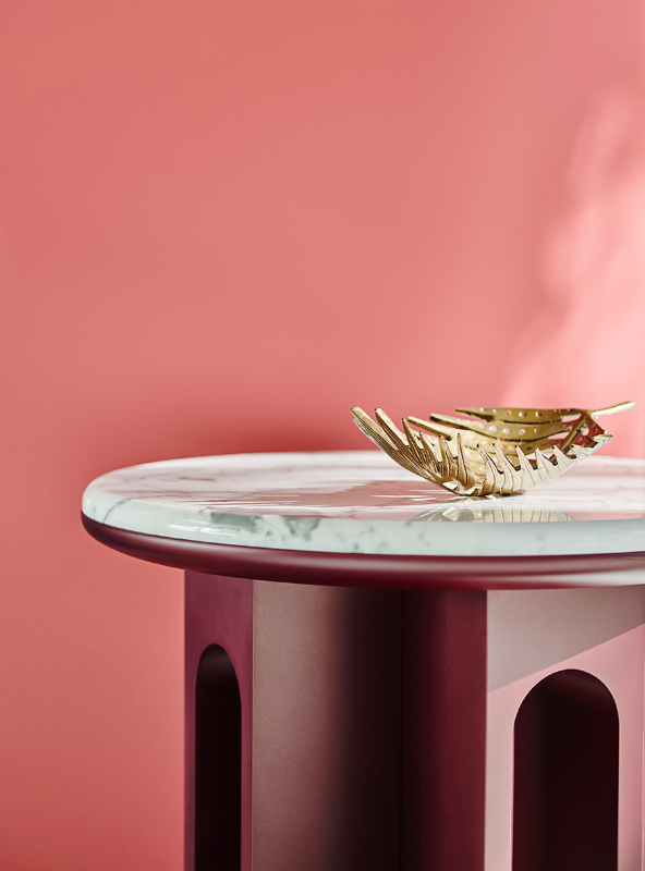 pink side table with white marble top with gold accent bowl in pink room