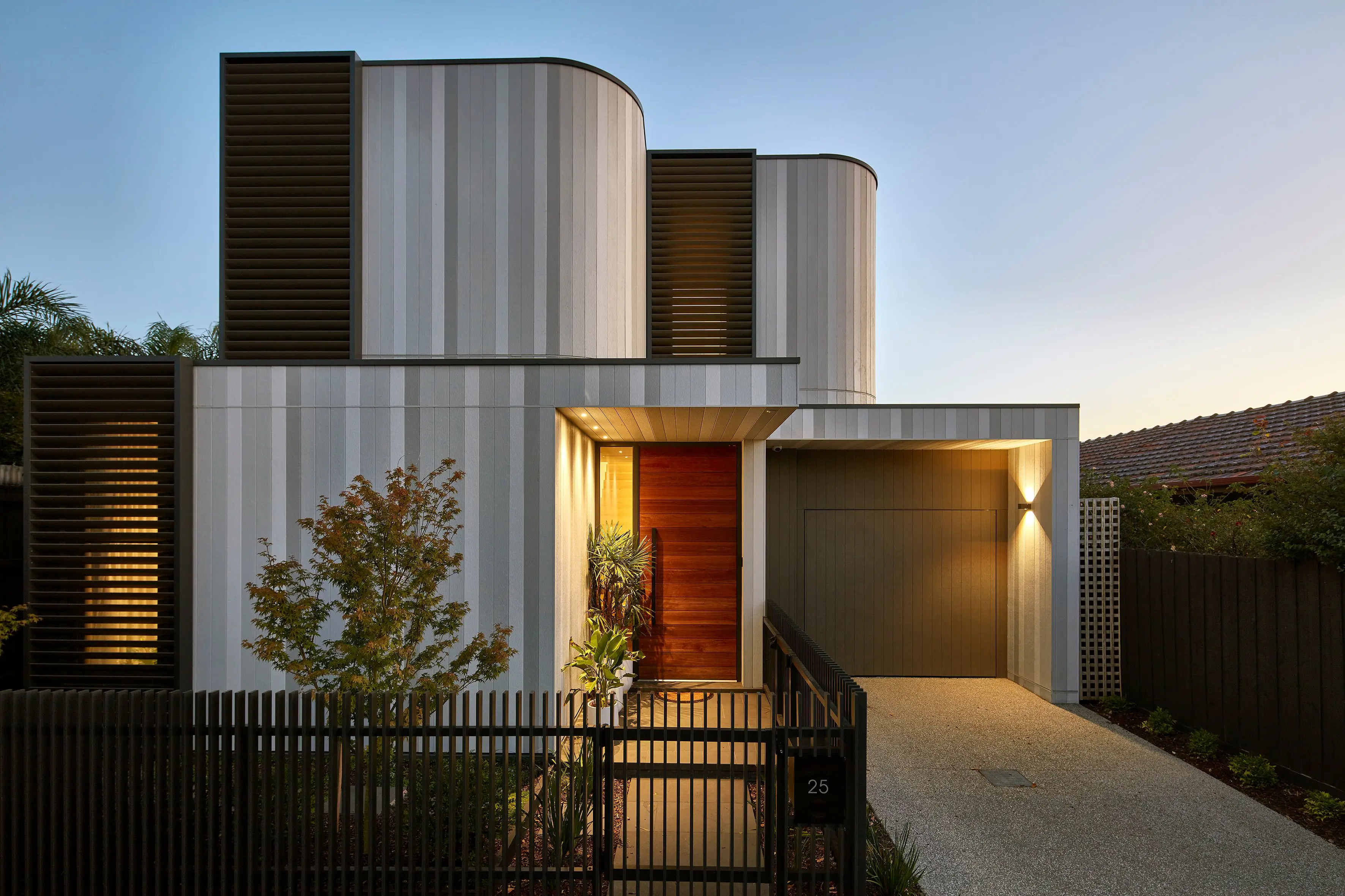 Curved double storey brown and aluminum house with timber door