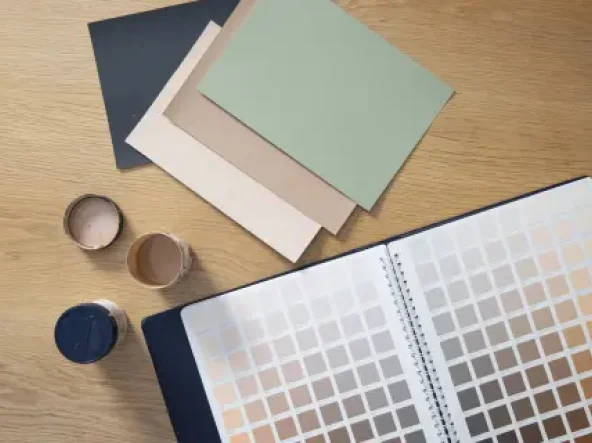 Dulux colour swatches, sample pots and World of colour atlas on a timber table.