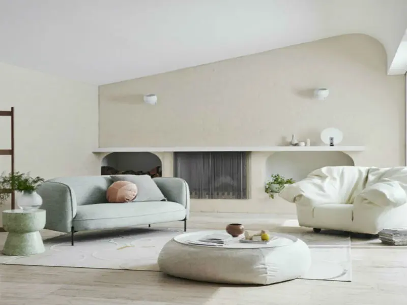 white and neutral living room with white armchair, light grey-green couch and neutral ottoman
