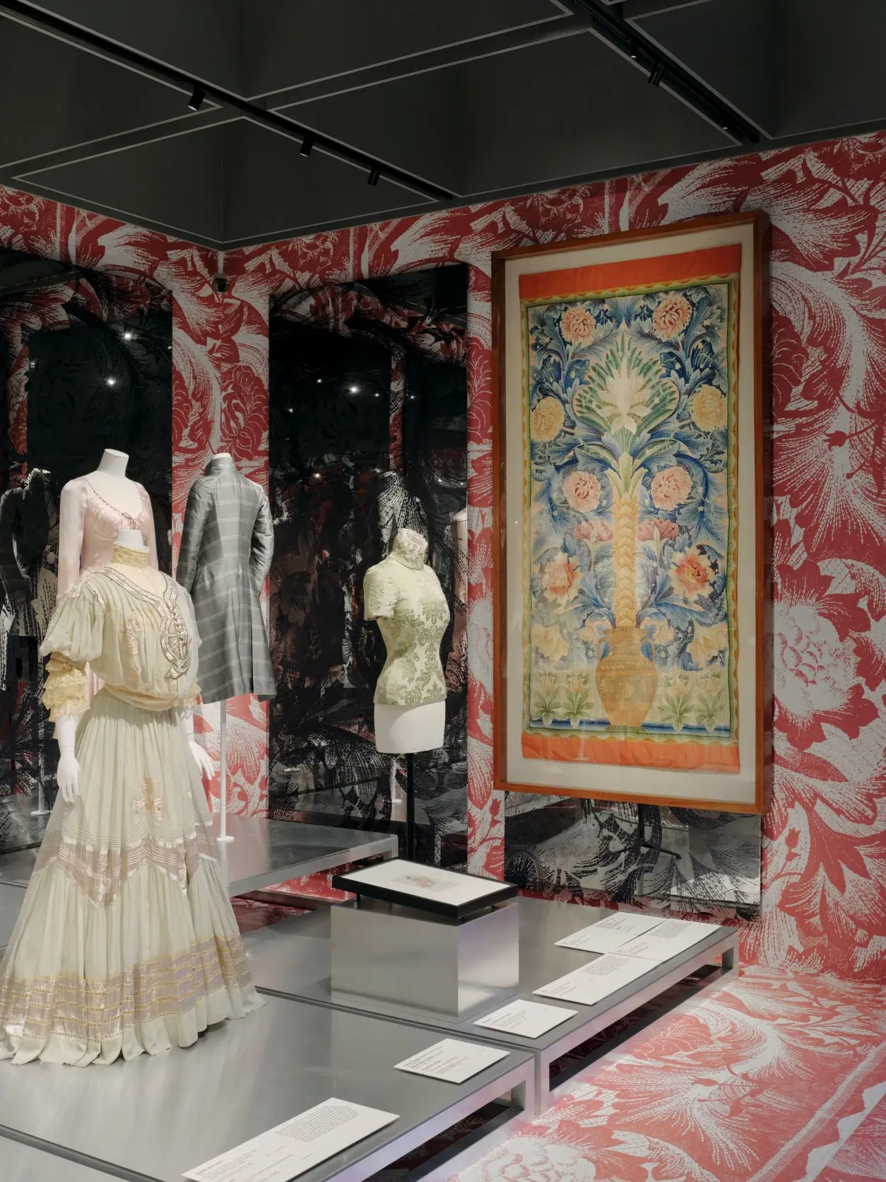 NGV Alexander McQueen mannequins alongside large artwork and decorative wallpaper