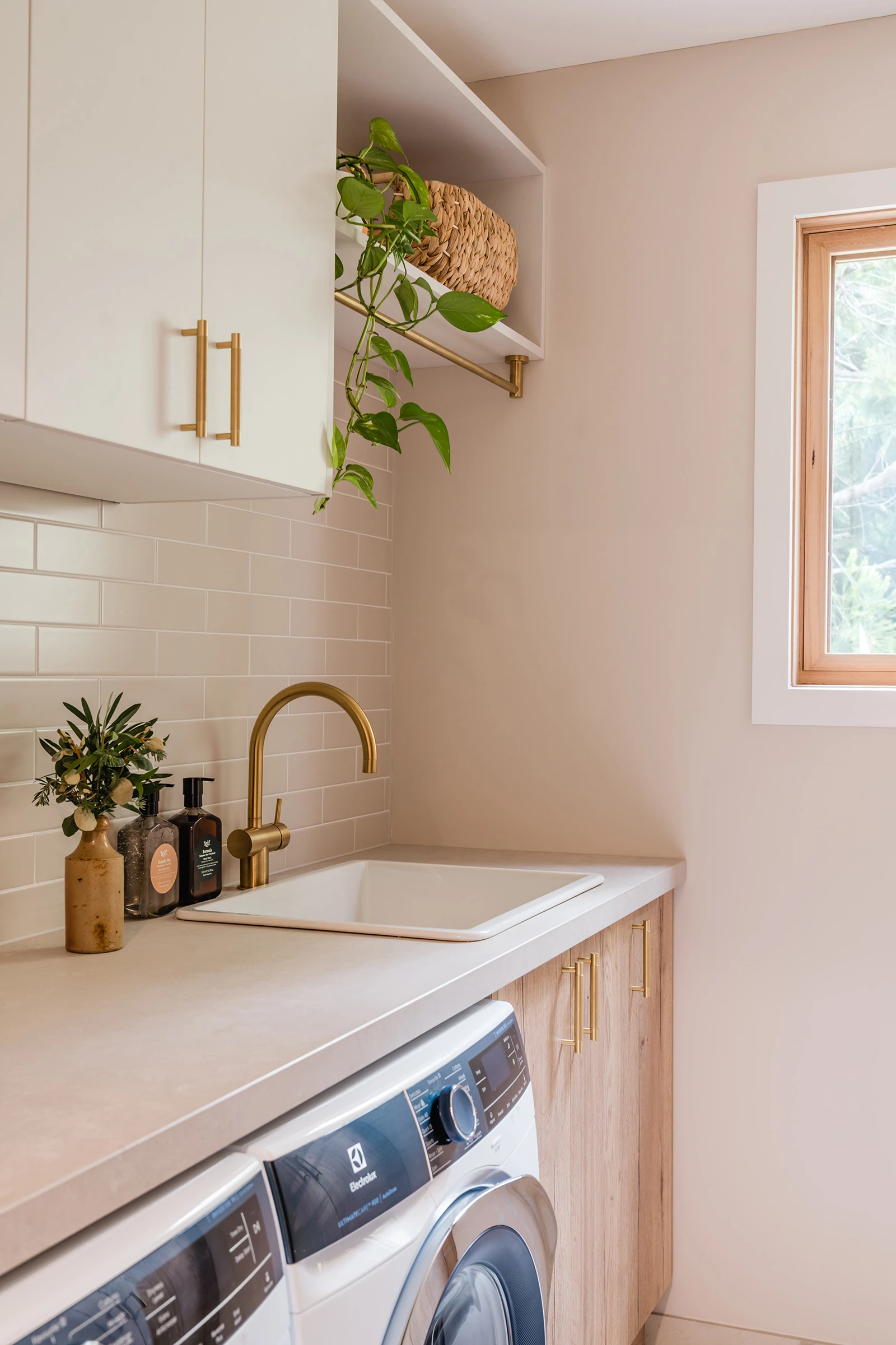 Neutral laundry with gold tapware and timber cabinetry