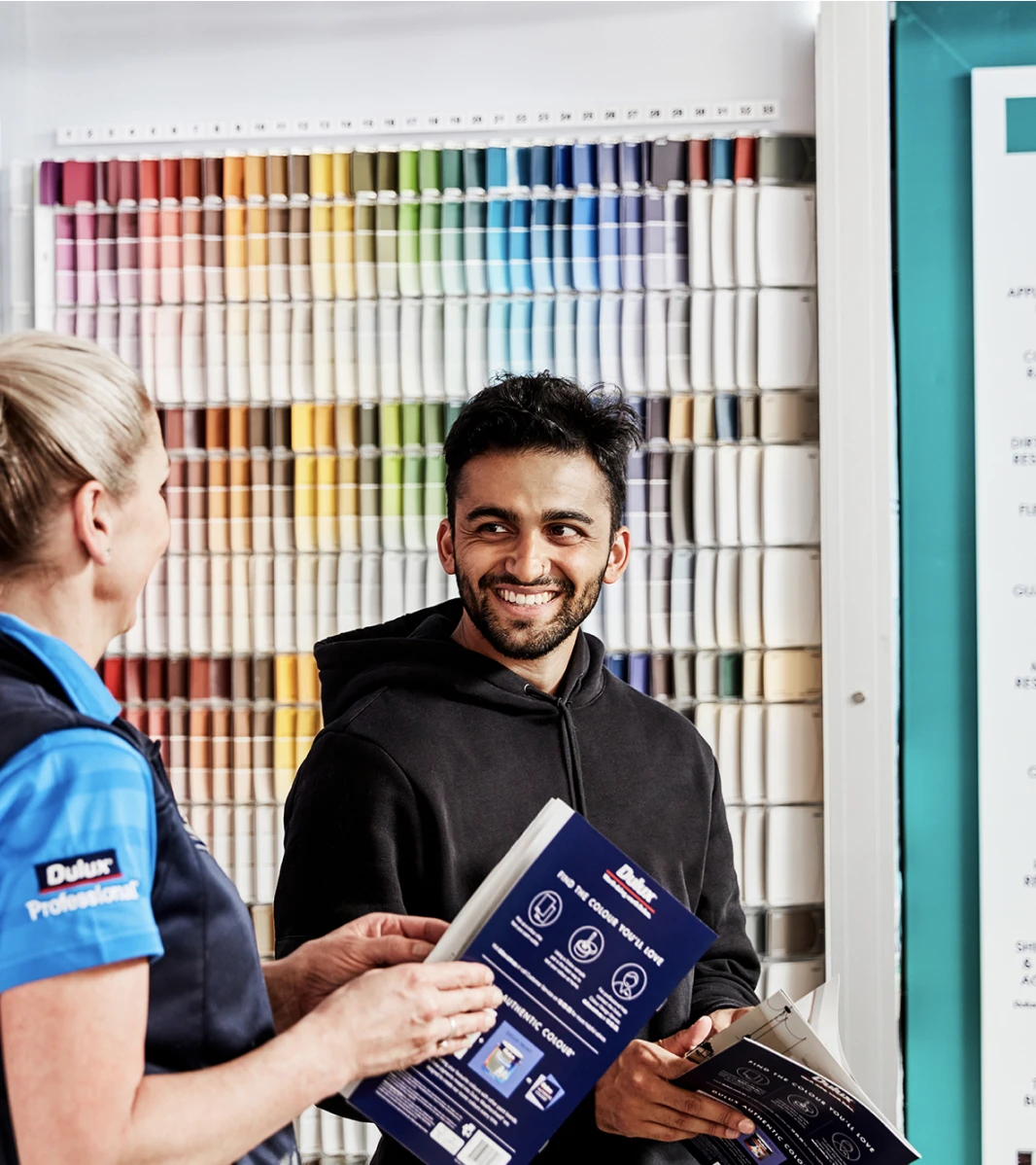 Dulux paint support crew member assisting a customer with their inquiry in front of colour board