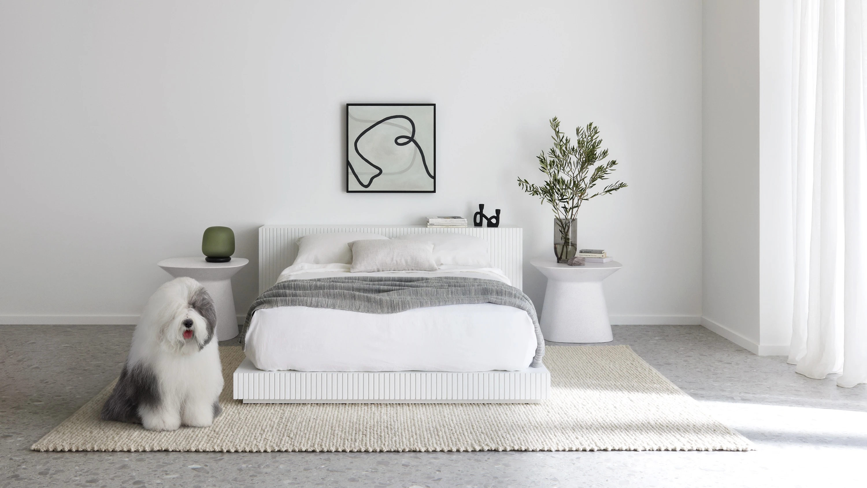 Bed and bedside tables against wall with artwork featured. Dulux dog in front of bed.