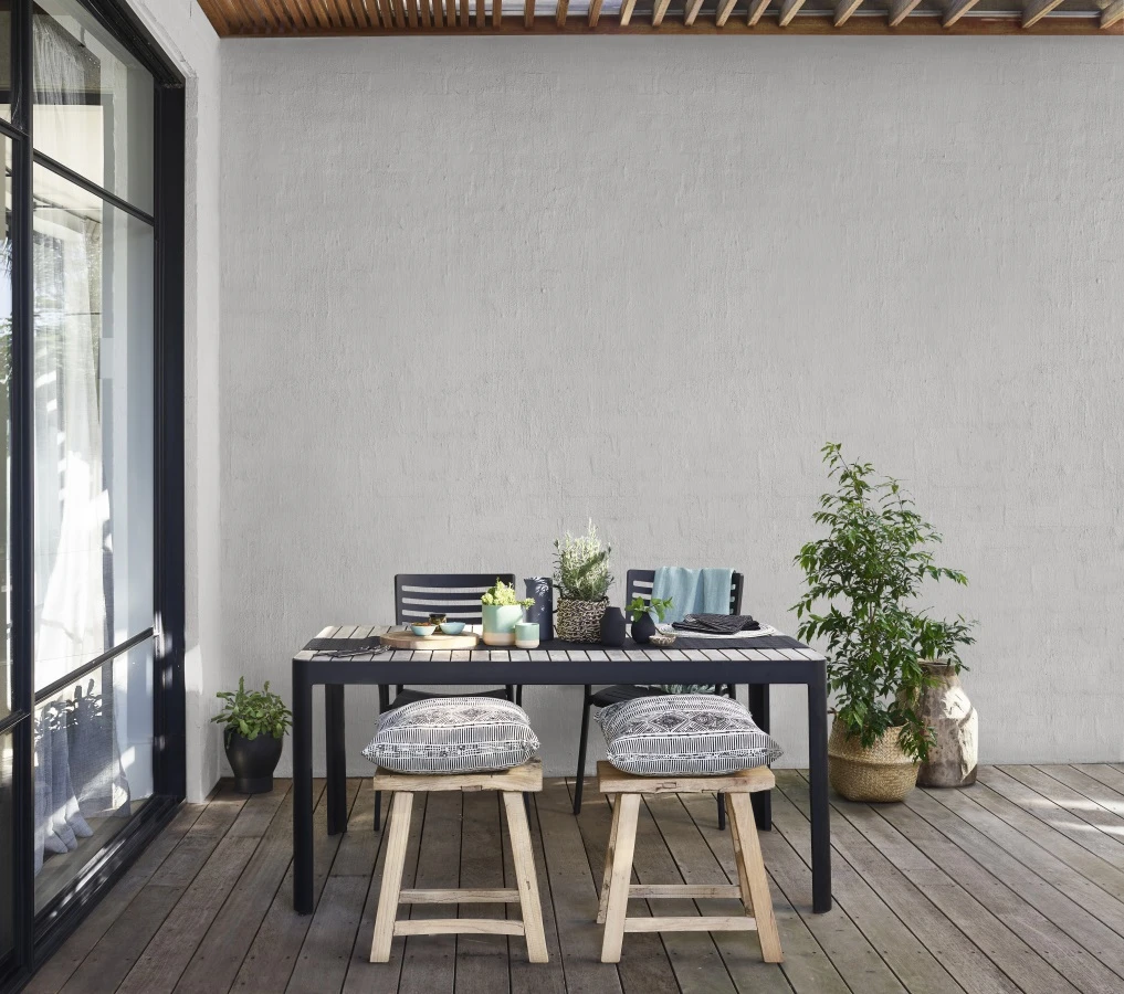 outdoor dining setting with grey textured wall in background
