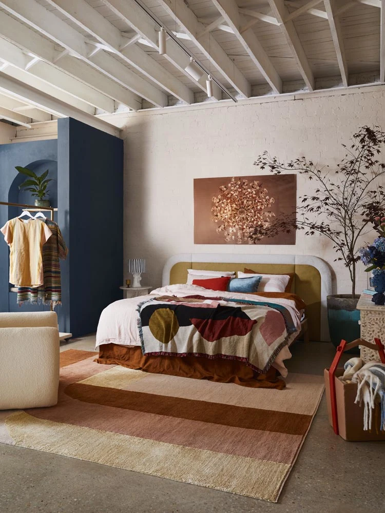 A vibrant, colourful bedroom with a blue feature wall and rust artwork
