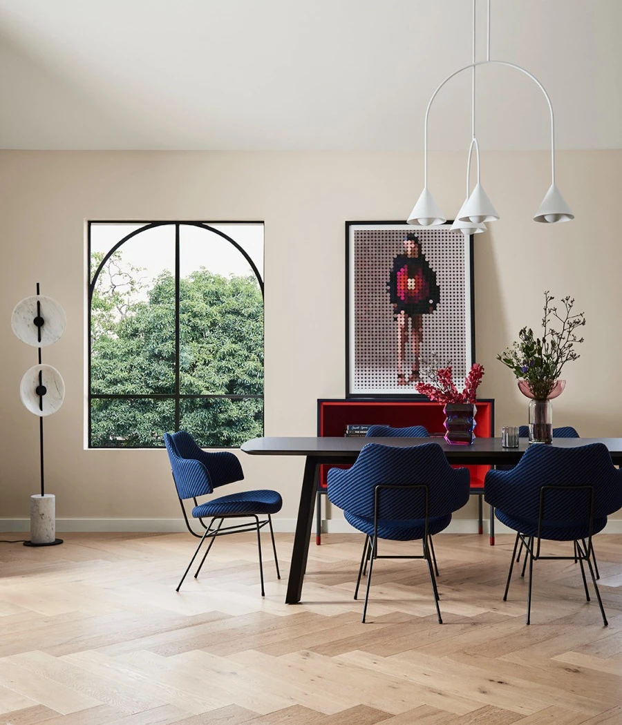 Dining room with black table with dark navy chairs. Wall features artwork and decorative items around.