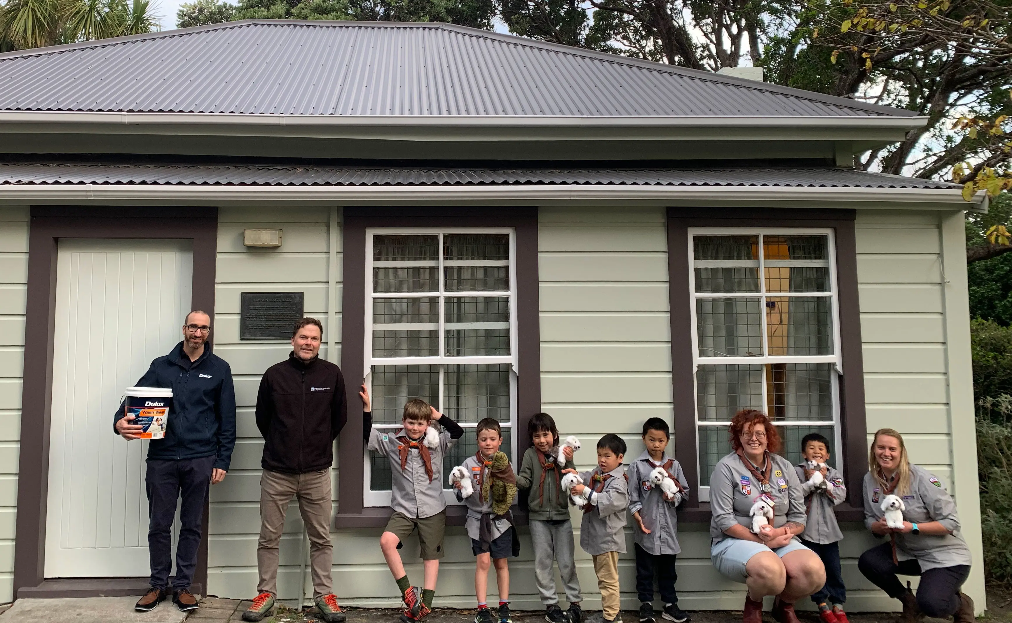 Children and adults stand in front of the newly painted scout hall