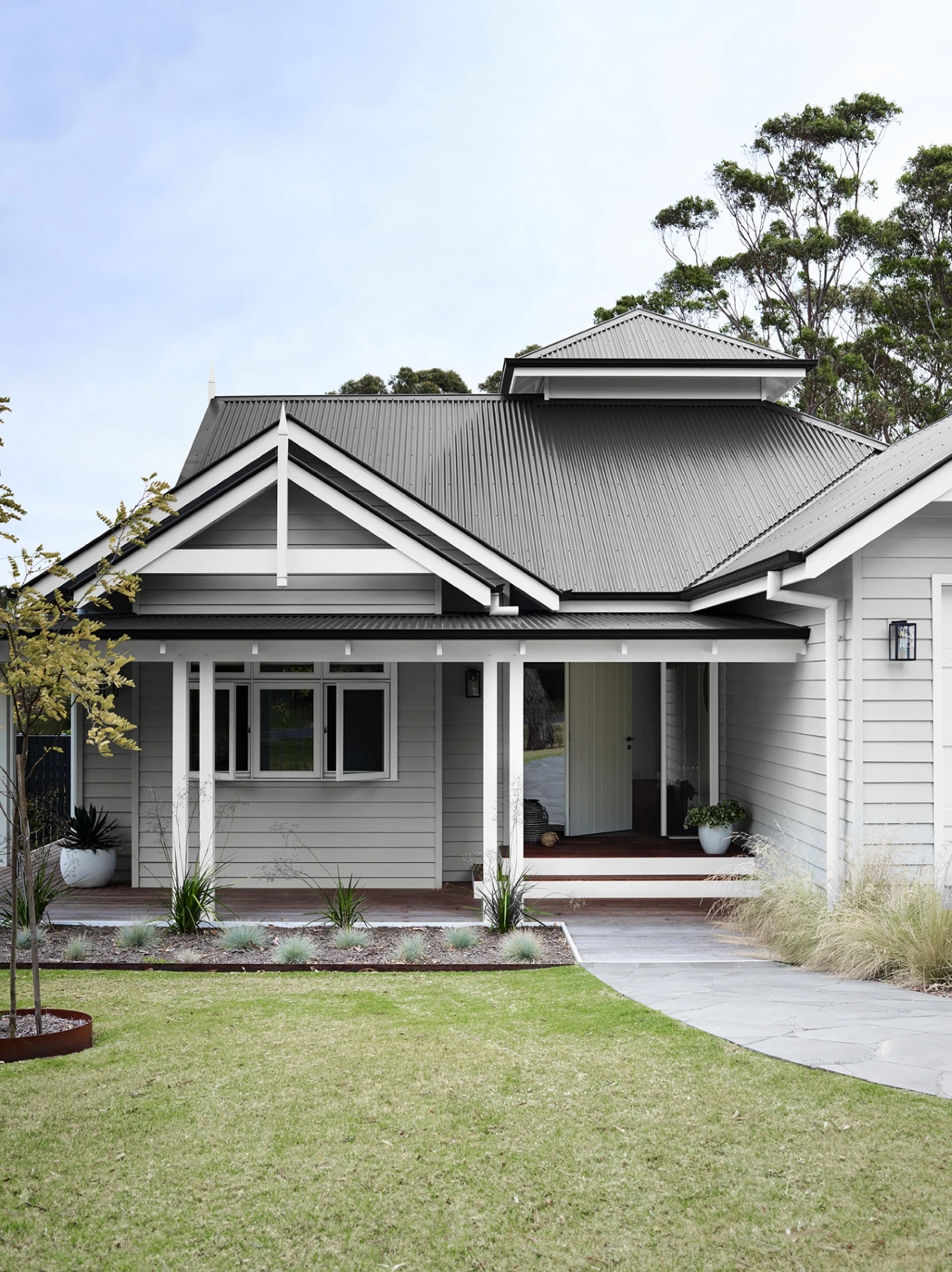 exterior grey weatherboard house with lawn. 
Taste of traditional weatherboard with Dulux Tranquil Retreat, Colorbond® Monument® and Vivid White™.