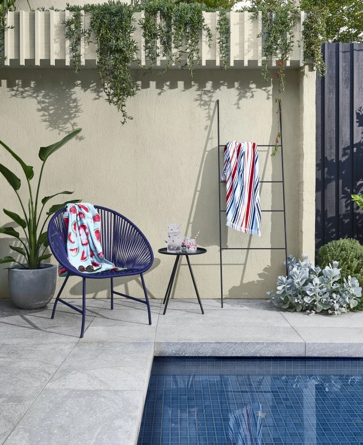 Pool with concrete pavers, blue chair and textured wall