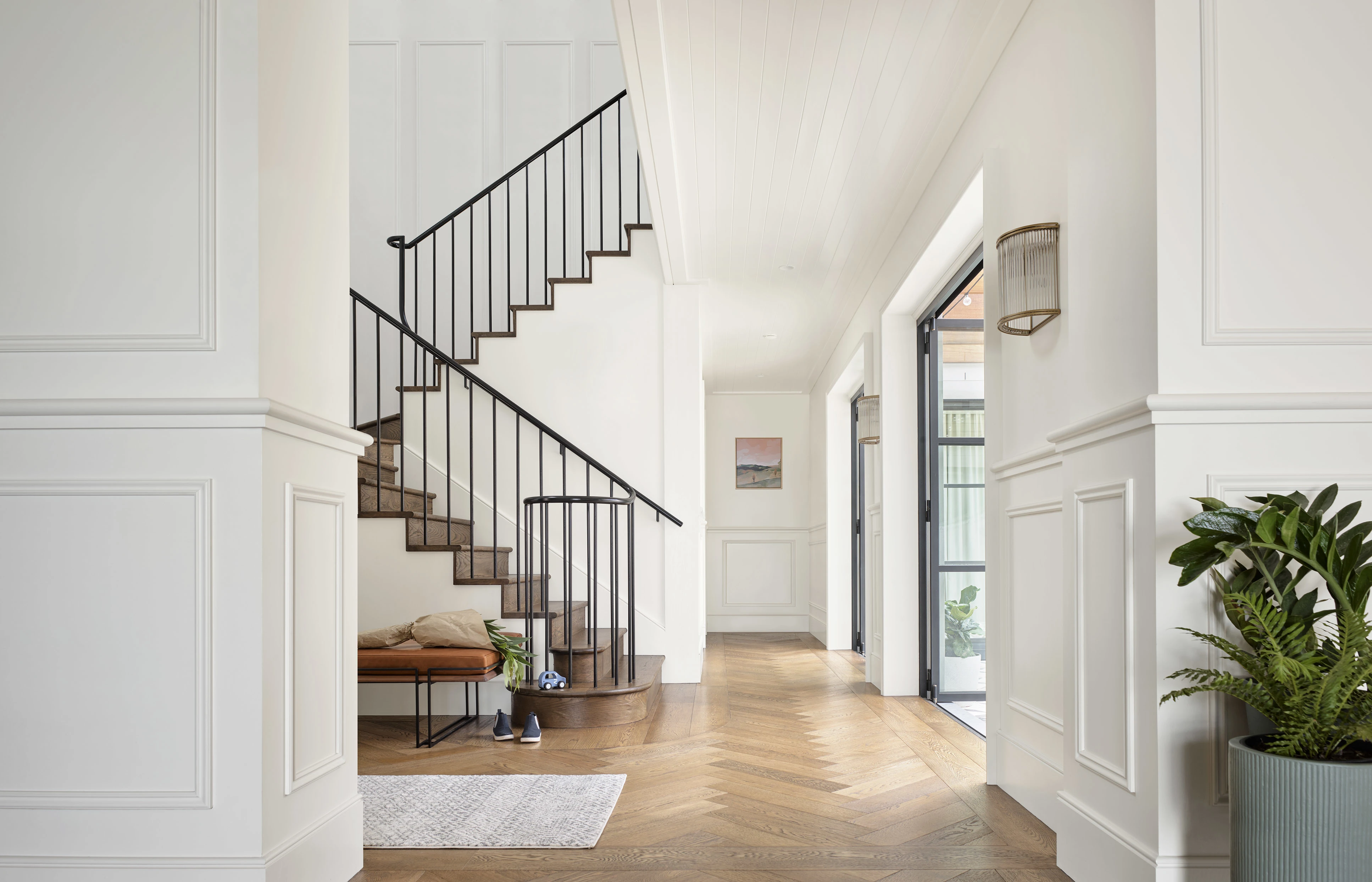 Entry way with stairs and wooden floors. The walls are white.