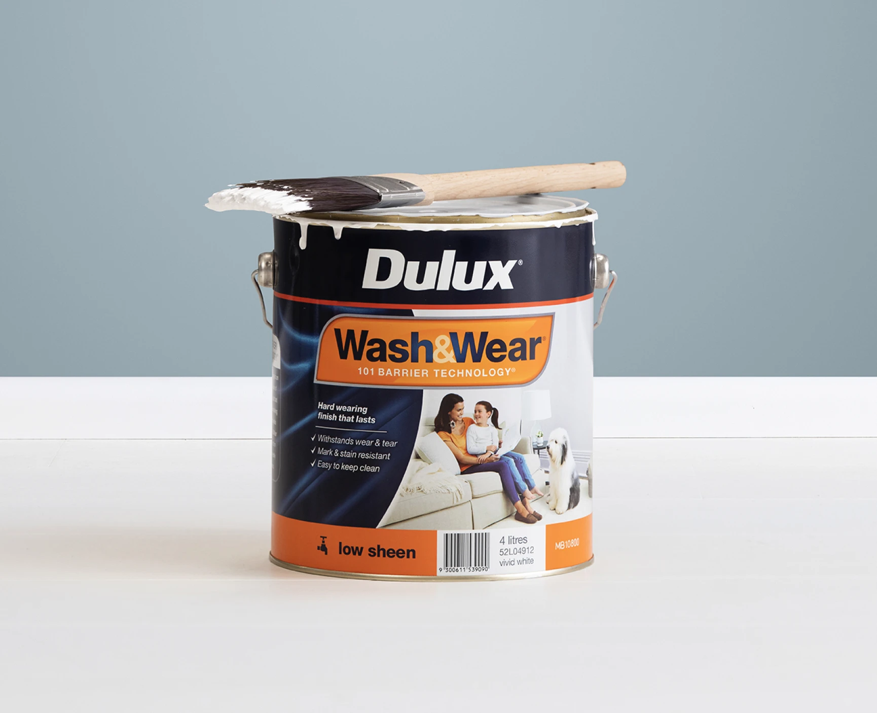 Dulux Wash&Wear tin with a paint brush on top in front of a painted interior wall.