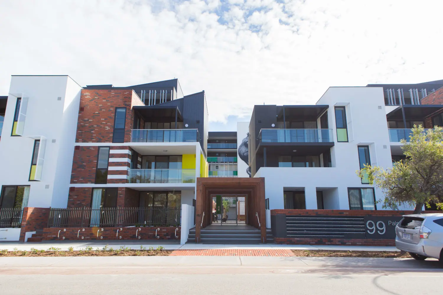 Triple-storey apartments in red brick and white render.