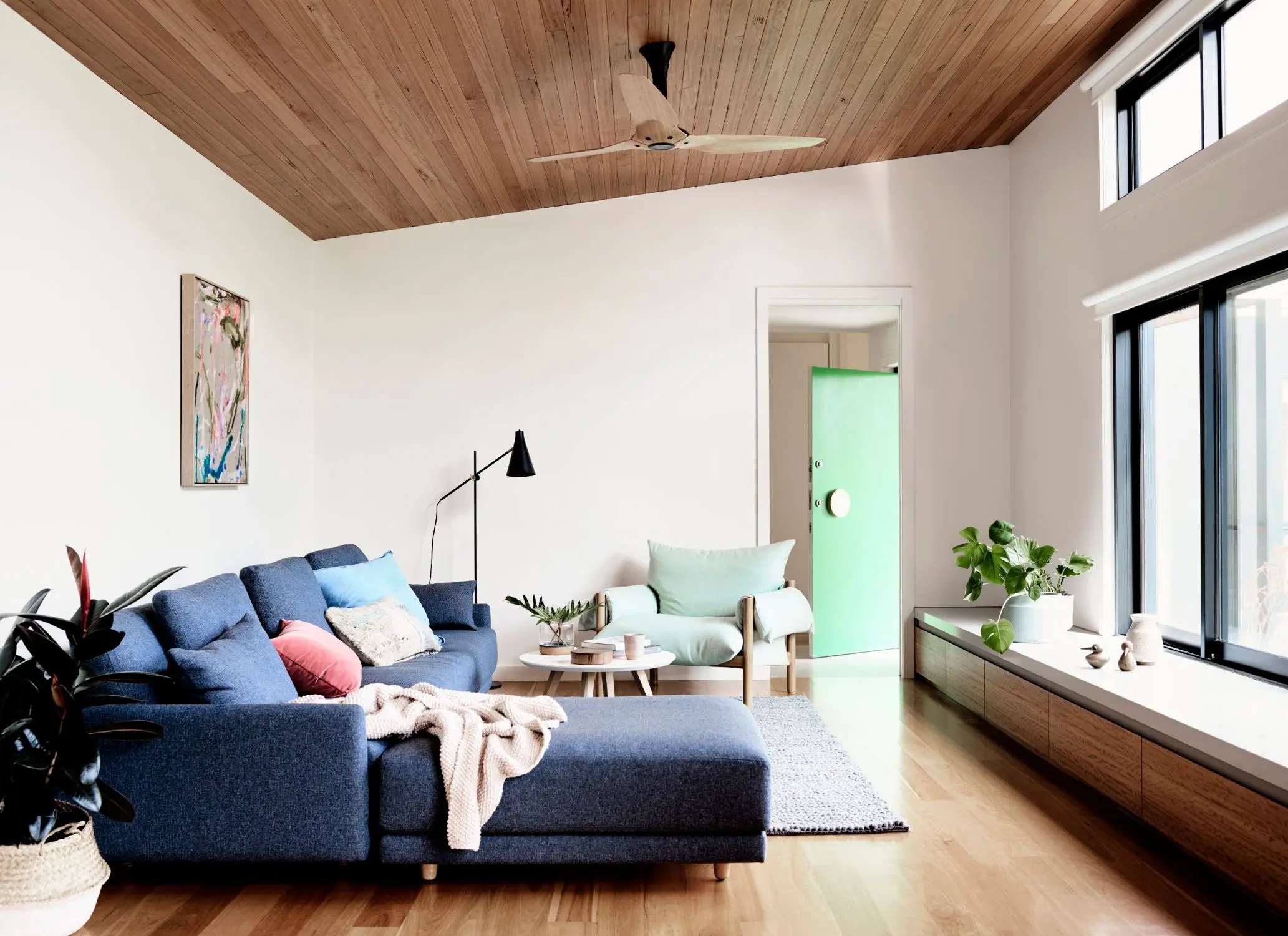 White living room with blue couch and hardwood floorboards