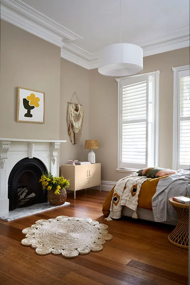 Cream bedroom with fireplace, white mantle, wooden floors, white windows