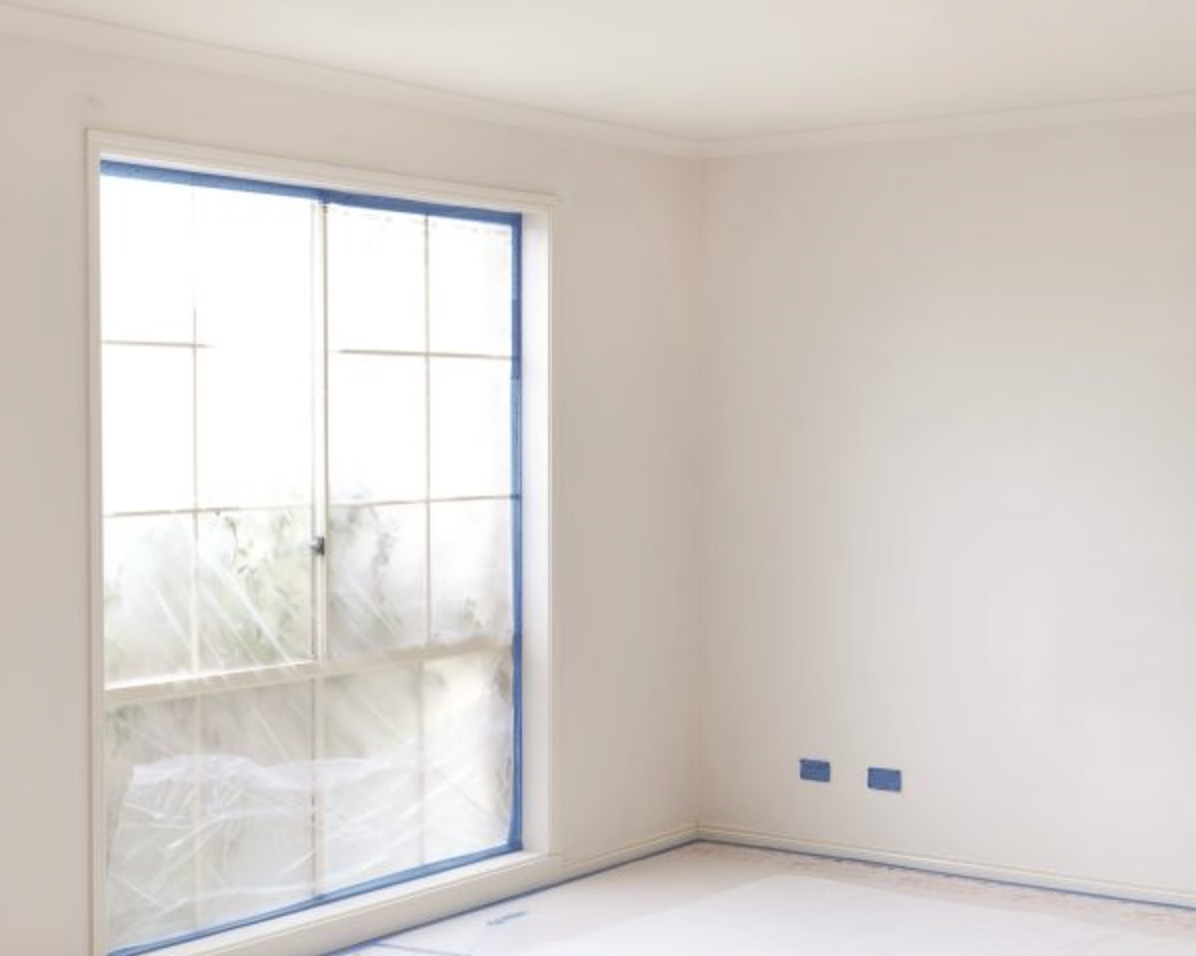 Painted white room with masking tape on the window trim and power sockets