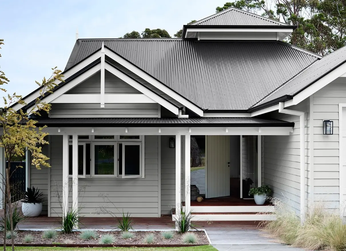 popular greys for exterior, white house with grey roof and timber decking, native grass garden