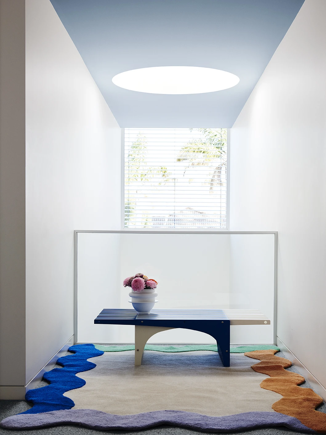 Blue bench seat under sky blue ceiling with white walls