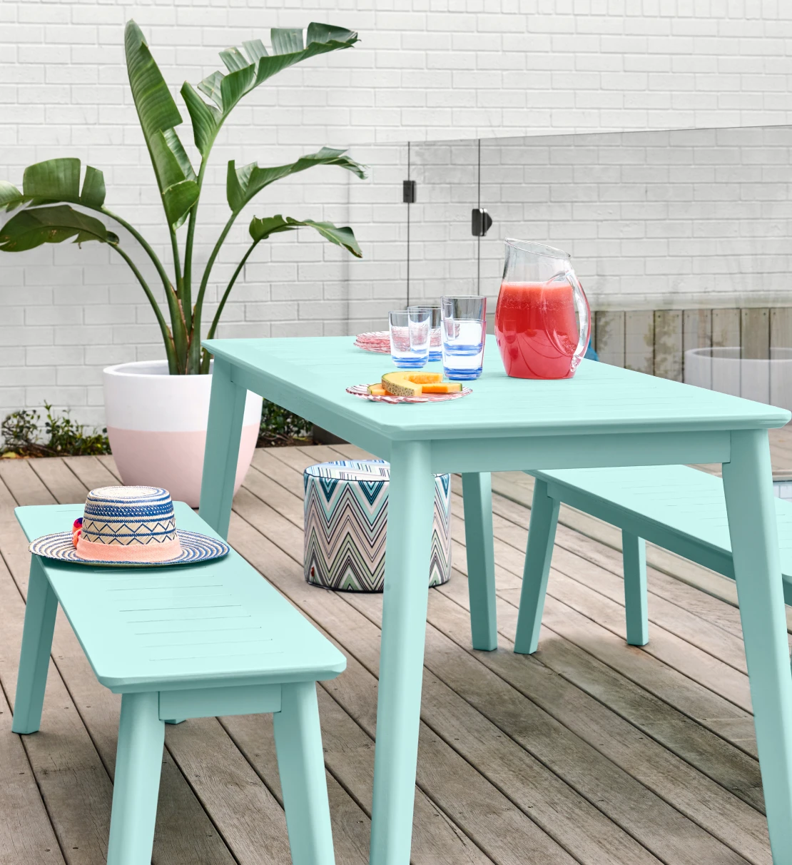 Outdoor entertaining area with Mint Twist coloured table and chairs on a deck in front of a pool fence and white brick wall.
