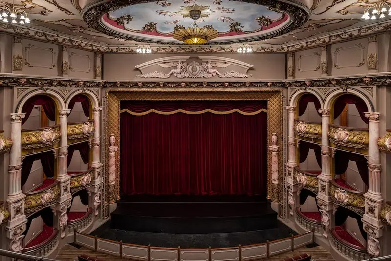 Looking down at the stage of the St James Theatre. There is a red curtain hanging down at the back of the stage.
