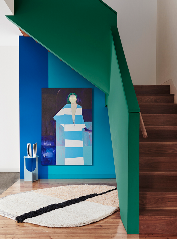 A blue wall and painting under a green staircase
