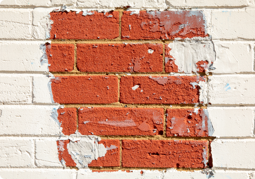 White wall with section of red bricks exposed.