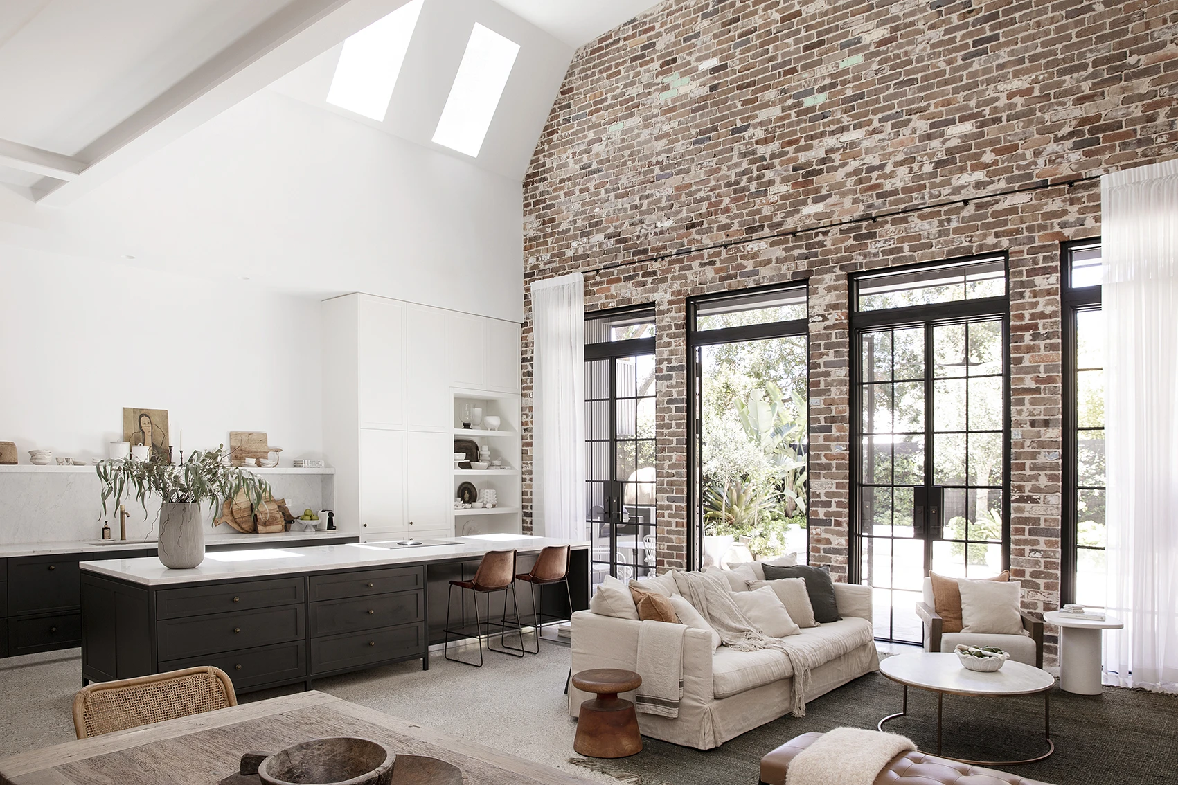 White living and dining room with recycled brick feature wall.