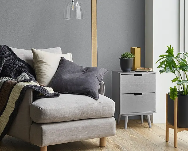 A grey couch with cushions and a blanket