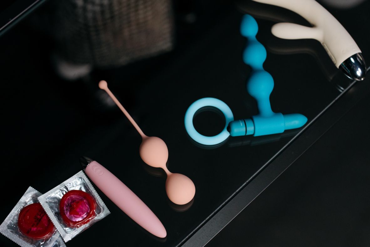 various sex toys and condoms on side table