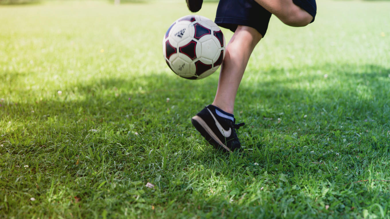 A soccer player practices heeling the ball up into the air.