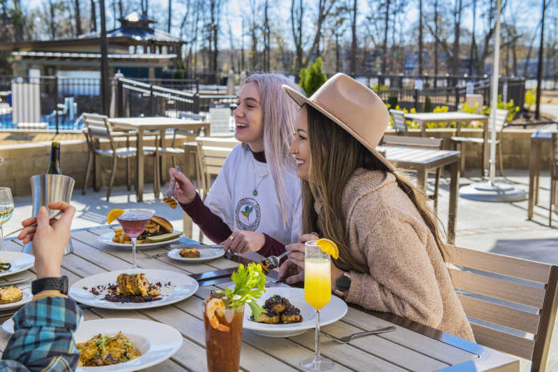 Two young women enjoy lunch with friends on the patio at Traditions on the Lake.