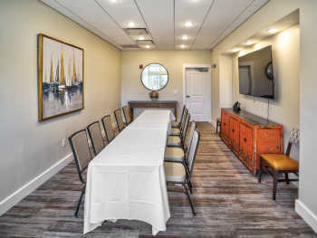 The private dining room at Traditions on the Lake, including a long banquet table with seating for 10 to 12 and a large, wall-mounted LED TV.