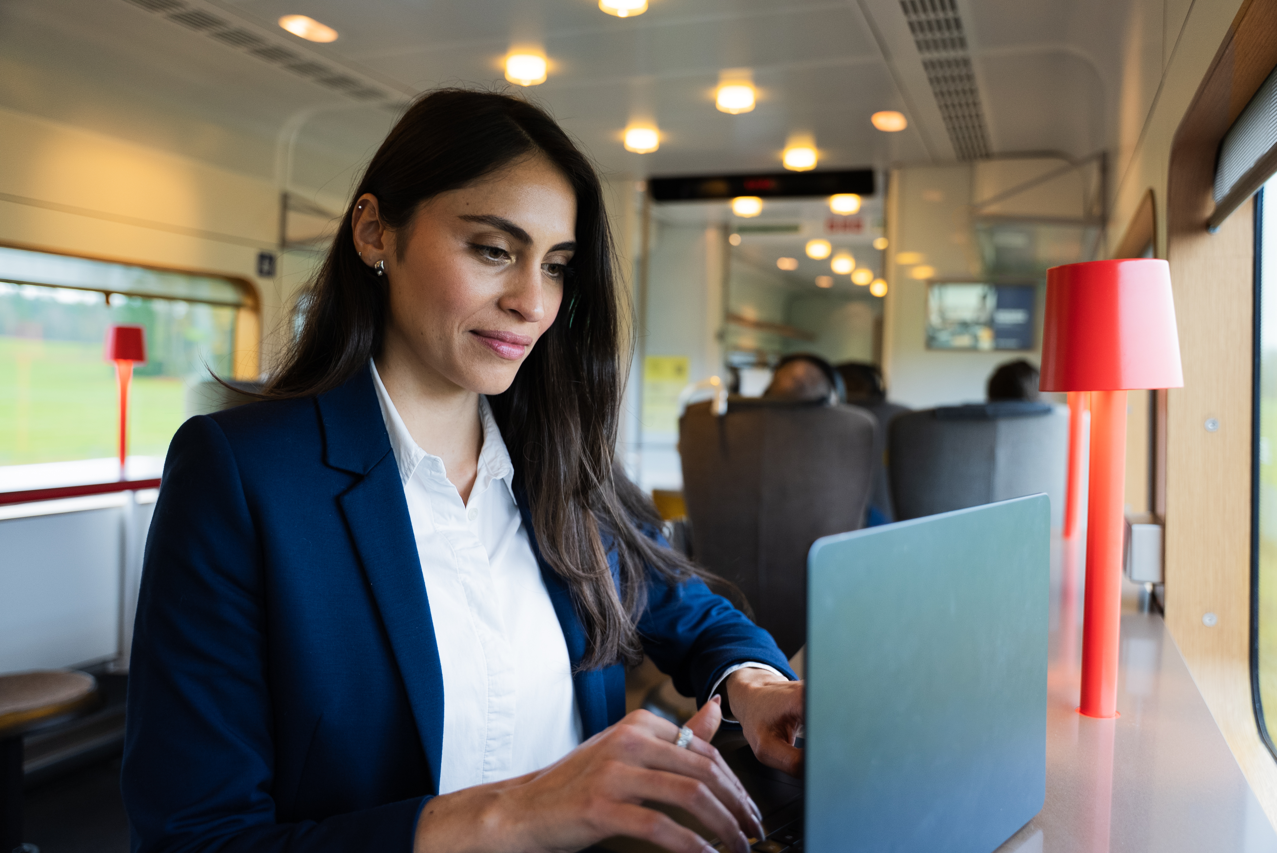 A business traveler working on a laptop at the bar seating onboard Arlanda express, illustrating the productive environment.