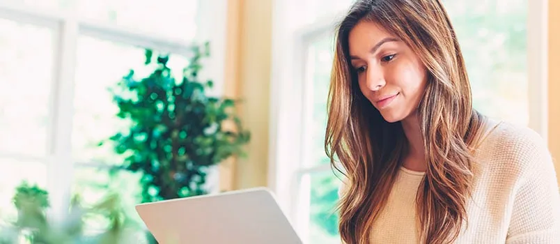 Woman in sweater looking at a laptop