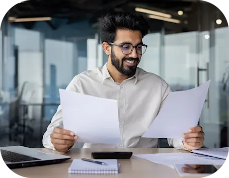 man with glasses holding paperwork while examining