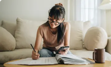 An image of a woman filing taxes on her phone while sitting on a couch.