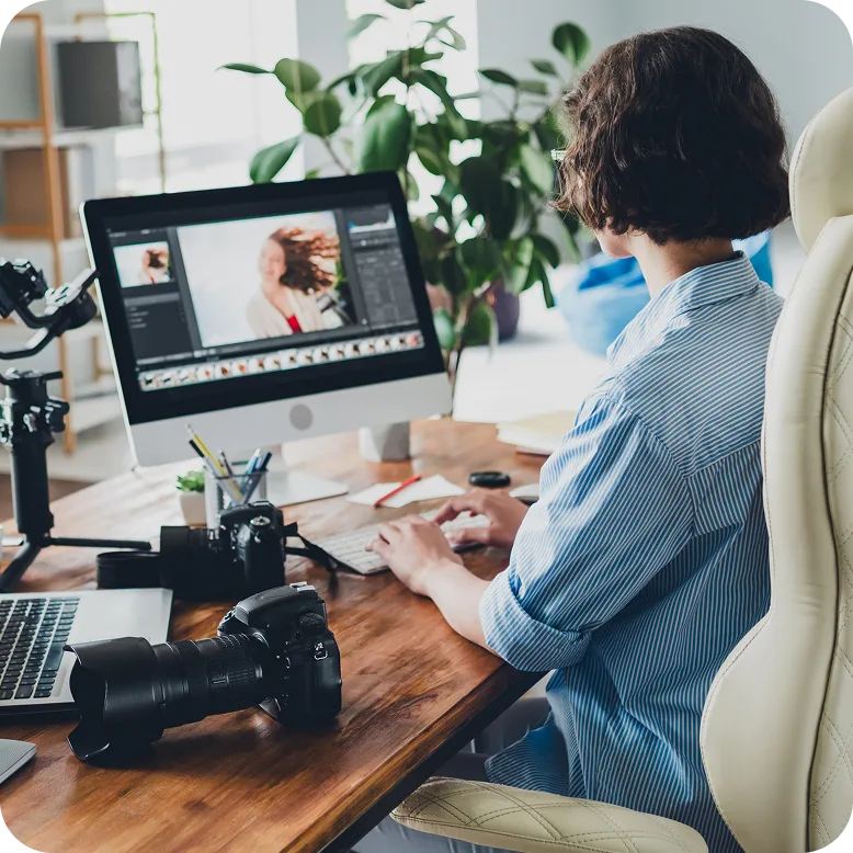 woman working on personal computer with a dslr camera next to her