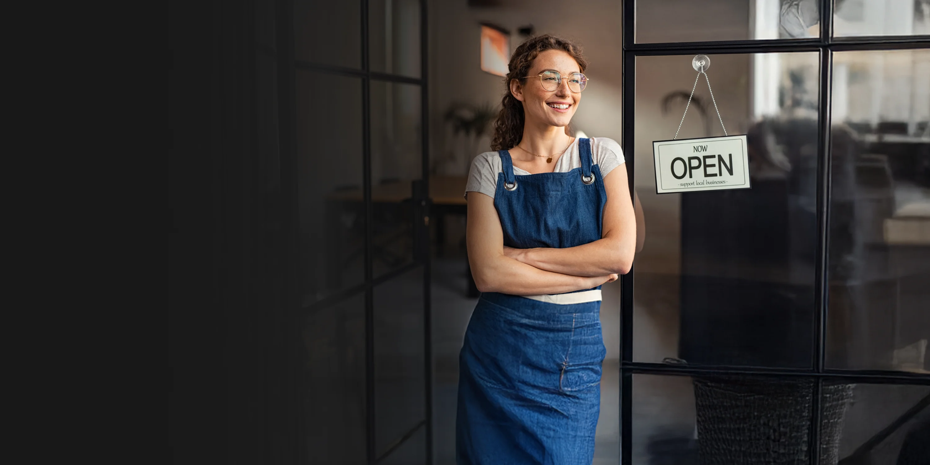 A woman leaning to a glass door next to an open sign