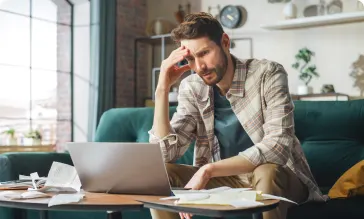 An image of a man doing his taxes on his laptop.