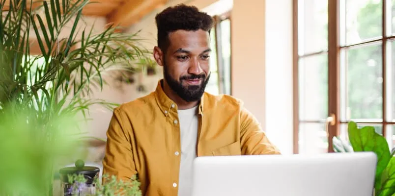 Man on computer surrounded by green plants