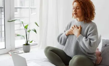 Woman meditating to remain calm amid natural disaster impact.