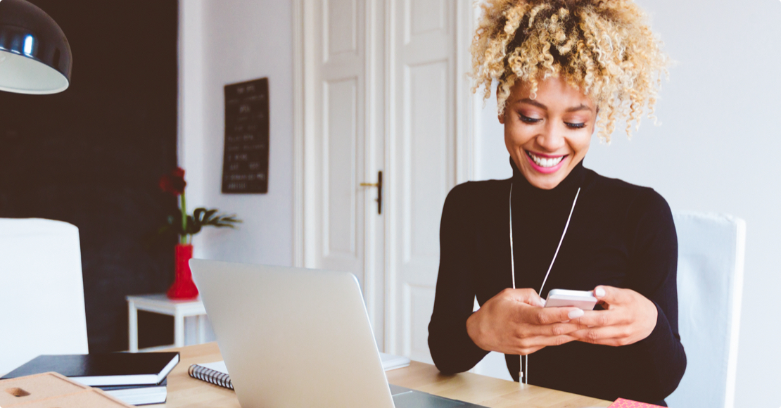 A self-employed business entrepreneur looking at her mobile phone and smiling