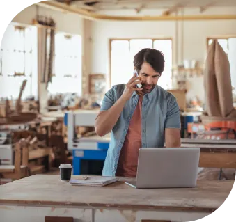 Image of a man looking at laptop while holding phone to ear