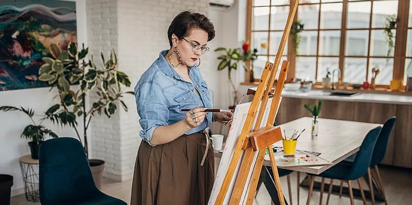 Woman in front of art easel with paint brush