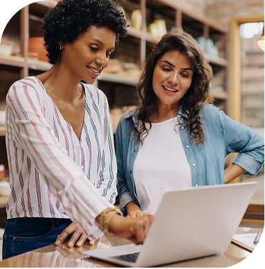 Two ladies talking while using laptop