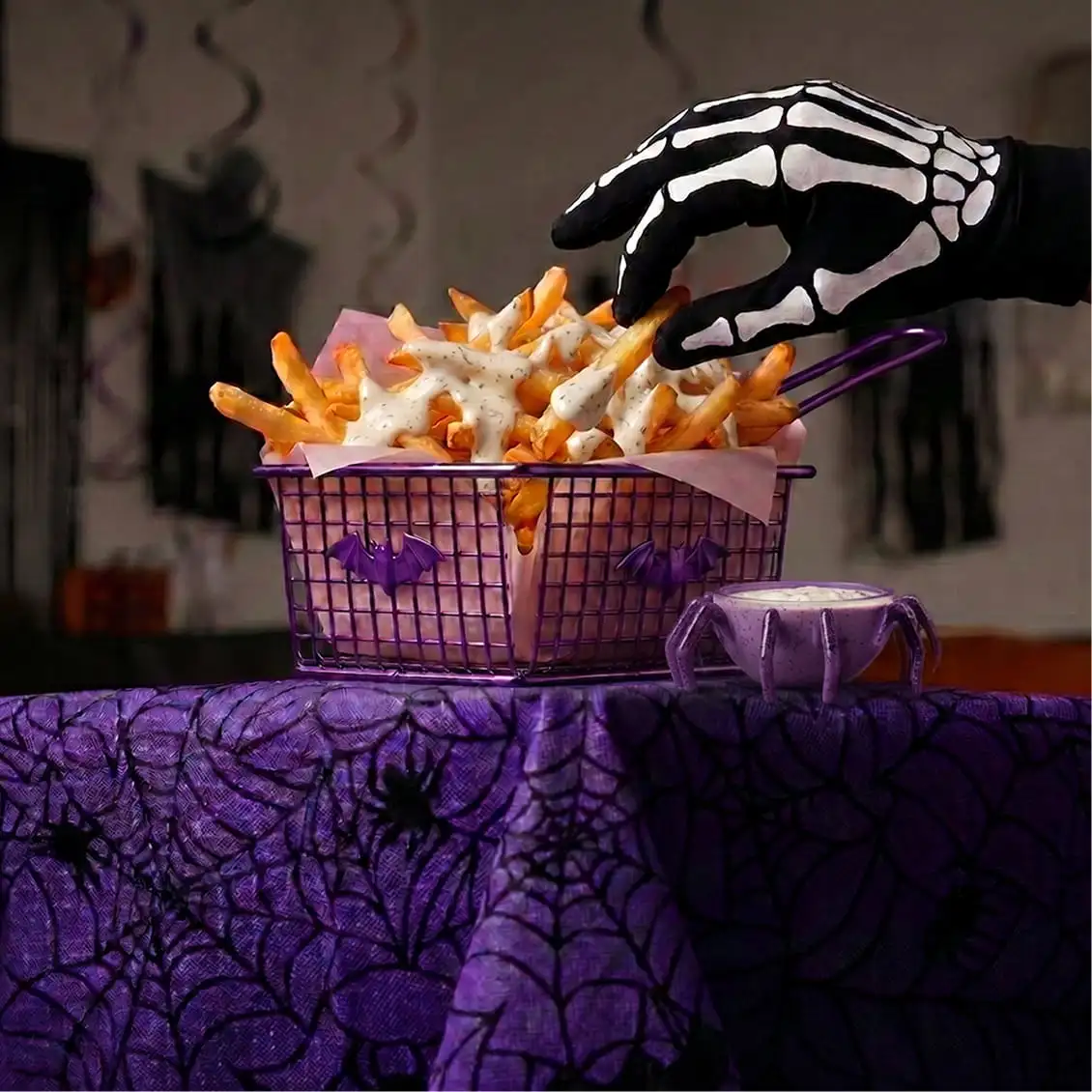 Skeleton-gloved hand reaching for Halloween fries with ranch dip and spooky decor
