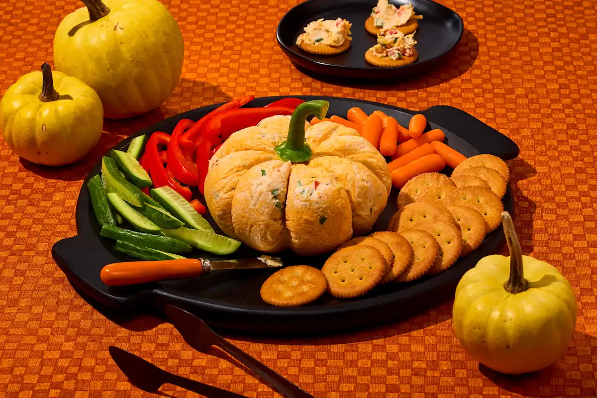 Pumpkin-shaped Hidden Valley Ranch cheeseball with crackers, carrots, cucumbers, and red peppers