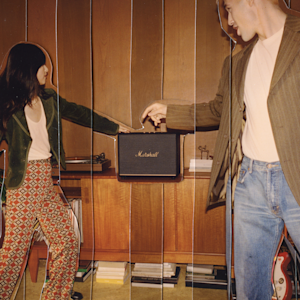 Un couple d'amis jouant de la musique et dansant autour de leur enceinte Acton III Black