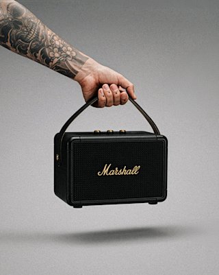 Une main tenant une enceinte portable Marshall KILBURN II noire.